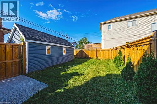 Detached garage with blue siding and white trim, featuring a dark shingle roof - 1231 Dunsmure Road, Hamilton, ON 