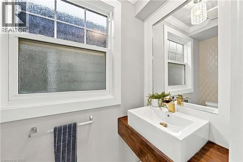 White rectangular vessel sink with a gold-finish faucet, set on a wood-finish floating vanity - 1231 Dunsmure Road, Hamilton, ON 
