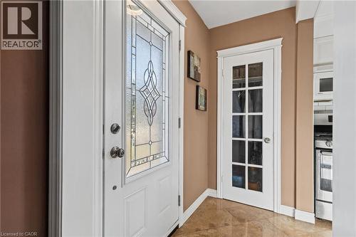 Entryway featuring a decorative glass front door, white trim, a multi-pane interior door, and polished tile flooring - 366 East 17Th Street, Hamilton, ON 