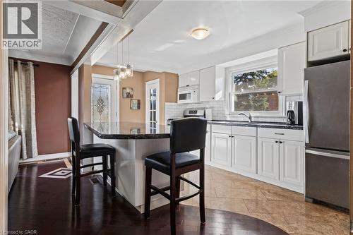 Kitchen featuring white cabinetry, dark stone countertops, subway tile backsplash, and stainless steel appliances - 366 East 17Th Street, Hamilton, ON 