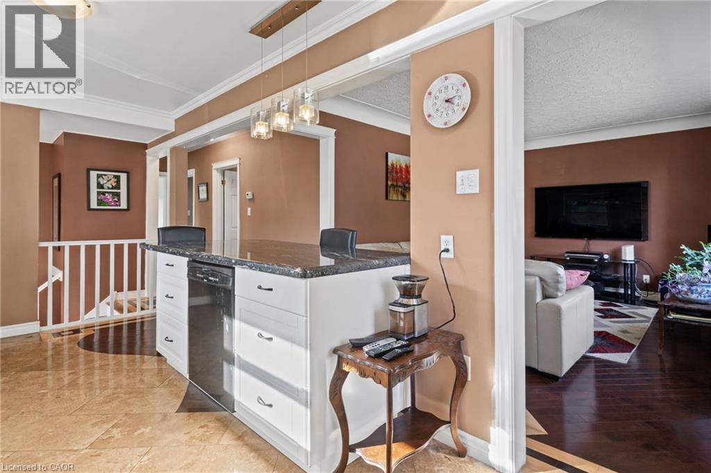 Kitchen island with dark countertop, integrated dishwasher, and white cabinetry - 366 East 17Th Street, Hamilton, ON