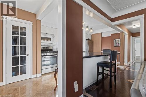 Sophisticated open-concept kitchen and dining area featuring warm taupe and white finishes, white cabinetry with glass-front doors, stainless steel built-in appliances, wood-finish flooring throughout - 366 East 17Th Street, Hamilton, ON 