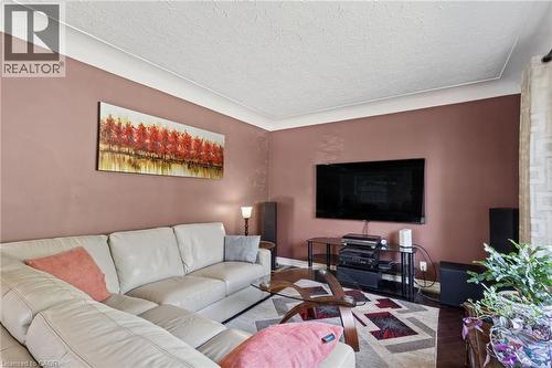 Wall-mounted television with media console, crown molding, and textured ceiling - 366 East 17Th Street, Hamilton, ON 