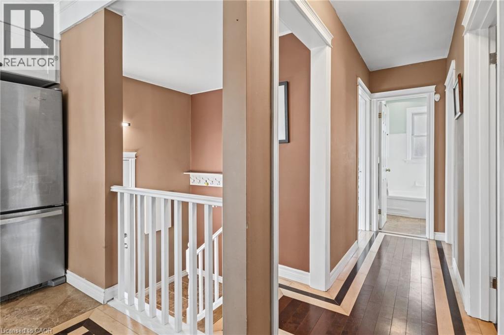 Hallway featuring wood-finish flooring with decorative inlay, white trim, and a recessed ceiling fixture - 366 East 17Th Street, Hamilton, ON