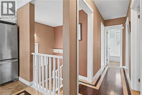 Hallway featuring wood-finish flooring with decorative inlay, white trim, and a recessed ceiling fixture - 366 East 17Th Street, Hamilton, ON 