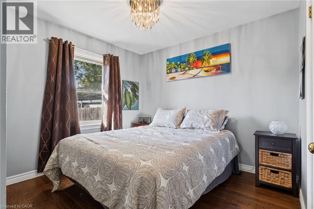 Hardwood-finish flooring, single window with brown drapes, and an overhead crystal chandelier - 366 East 17Th Street, Hamilton, ON