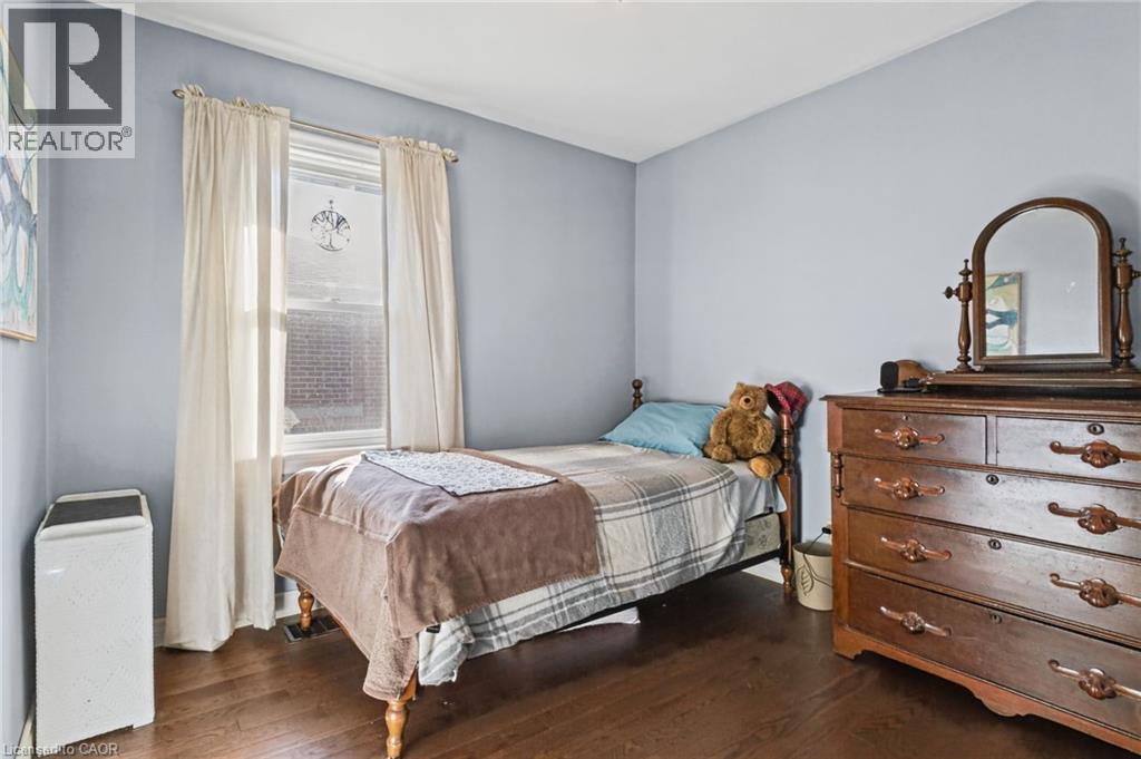 Hardwood flooring, painted walls, single window, classic wooden dresser with mirror, and white trim - 366 East 17Th Street, Hamilton, ON