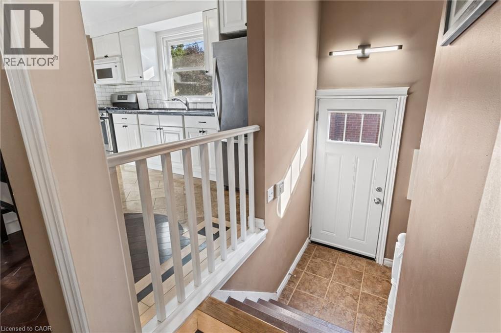 Kitchen featuring white cabinetry, subway tile backsplash, and dark countertops - 366 East 17Th Street, Hamilton, ON