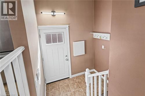 Entryway featuring a white paneled door with window inserts, tile flooring, and a modern wall-mounted light fixture - 366 East 17Th Street, Hamilton, ON 
