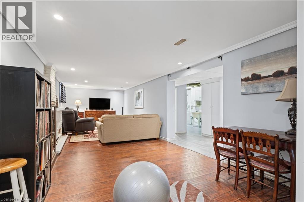 Recessed lighting illuminates this space, featuring wood-finish flooring, crown molding, and a painted brick wall - 366 East 17Th Street, Hamilton, ON