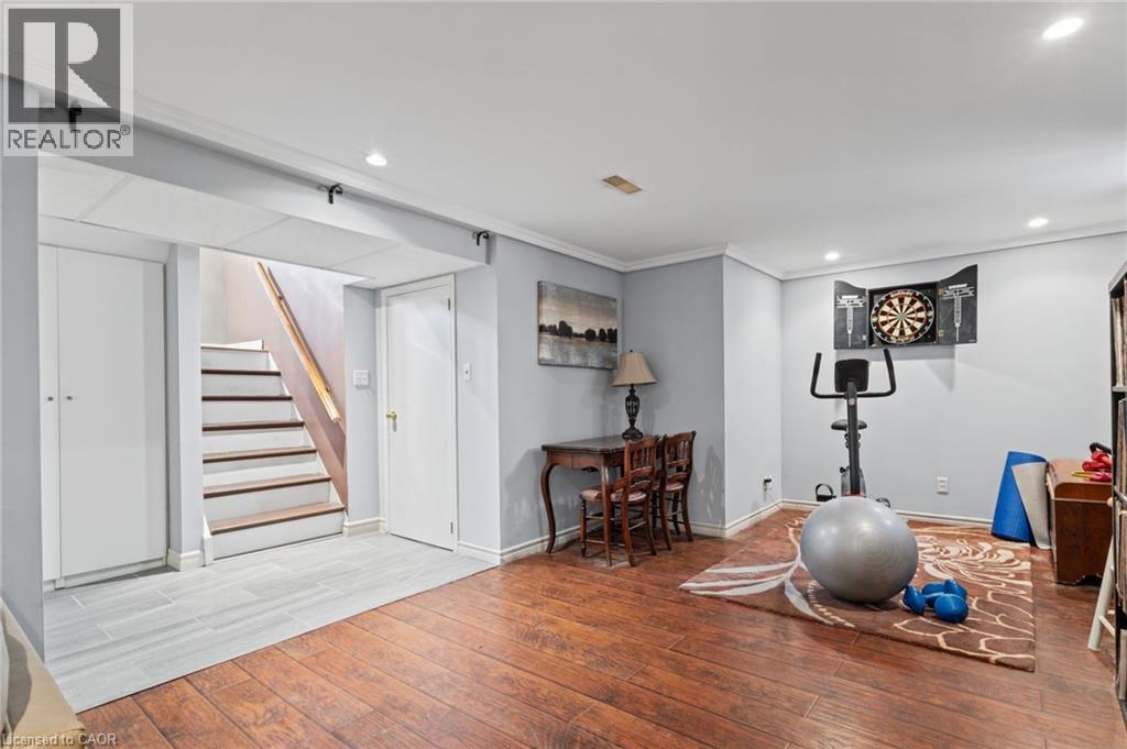 Finished basement featuring hardwood-finish flooring, recessed ceiling lighting, and multiple functional zones including a recreation area with built-in shelving and storage - 366 East 17Th Street, Hamilton, ON