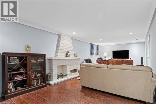 Expansive room featuring wood-finish flooring, a white brick fireplace, recessed lighting, and crown molding - 366 East 17Th Street, Hamilton, ON 