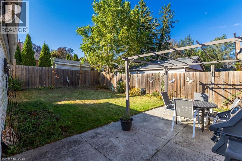 Expansive backyard featuring a concrete patio, a pergola, a manicured lawn, and a privacy fence - 366 East 17Th Street, Hamilton, ON
