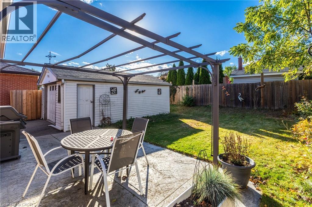 Patio area with a metal pergola, concrete hardscaping, and a detached shed - 366 East 17Th Street, Hamilton, ON
