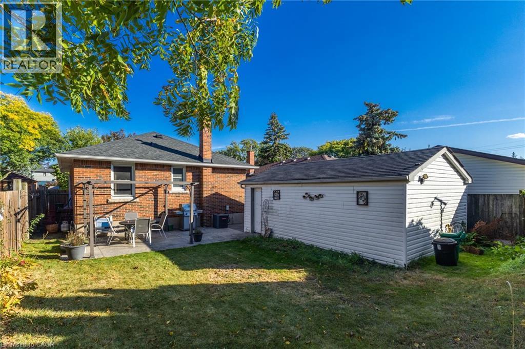 Expansive grassy yard with a concrete patio, brick exterior, and detached garage - 366 East 17Th Street, Hamilton, ON