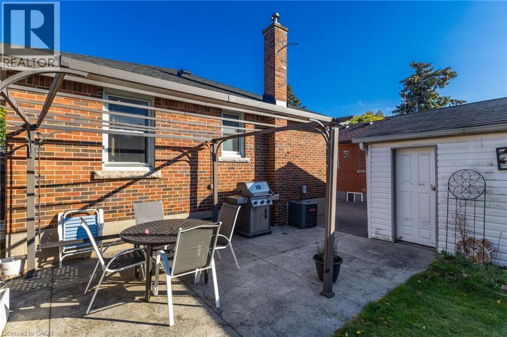 Brick exterior with a prominent chimney, concrete patio area, and a permanent gazebo structure - 366 East 17Th Street, Hamilton, ON