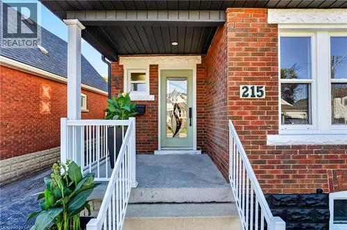 Brick exterior with white window trim, concrete steps, and a covered front entry - 215 Paling Avenue, Hamilton, ON 