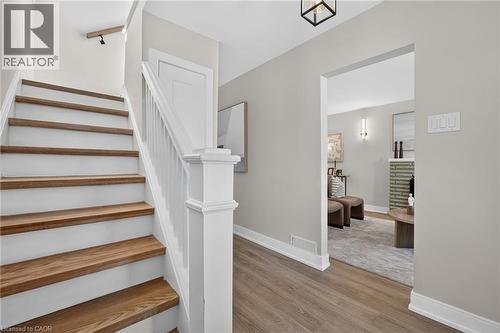Wood-finish flooring, staircase with wood treads and white risers, white painted balusters and newel post, recessed lighting, and a black metal-framed ceiling light fixture - 215 Paling Avenue, Hamilton, ON 