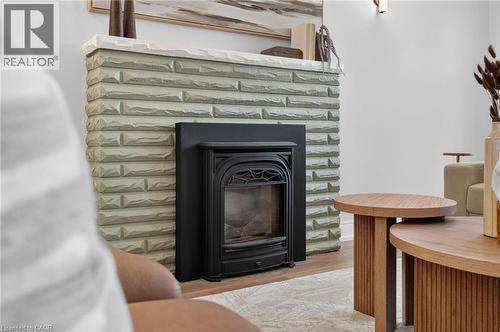 Fireplace featuring a light-colored brick surround, white mantel, and a black insert - 215 Paling Avenue, Hamilton, ON 