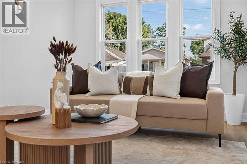Hardwood-finish flooring, white wall paint, wall-mounted light fixture, and multiple windows with white trim - 215 Paling Avenue, Hamilton, ON 