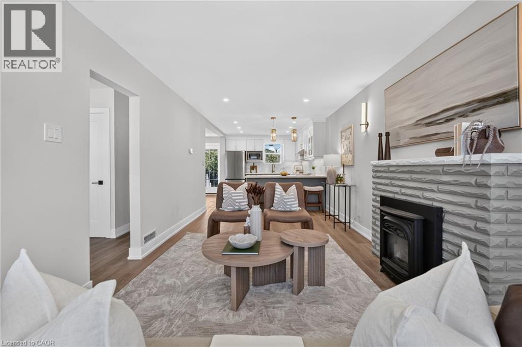 Living room with a stone-clad fireplace and wood-finish flooring - 215 Paling Avenue, Hamilton, ON
