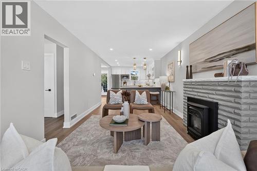 Living room with a stone-clad fireplace and wood-finish flooring - 215 Paling Avenue, Hamilton, ON 