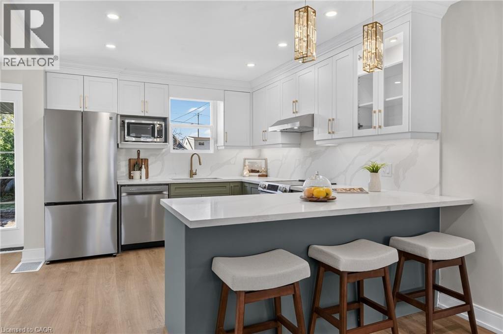 Kitchen featuring stainless steel appliances, white shaker cabinetry, wood-finish flooring, and a stone-finish countertop - 215 Paling Avenue, Hamilton, ON