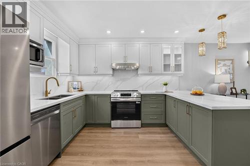 Two-tone cabinetry, stainless steel appliances, white countertops, wood-finish flooring, and recessed lighting - 215 Paling Avenue, Hamilton, ON 