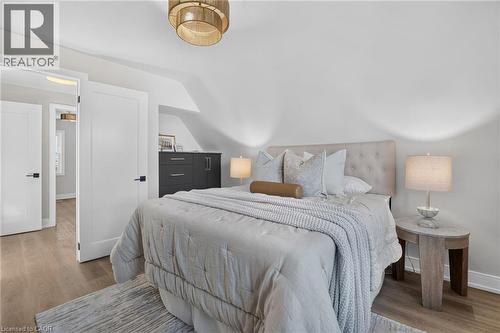 Upholstered headboard, wood-finish flooring, built-in dresser, contemporary ceiling fixture, and white interior doors with dark hardware - 215 Paling Avenue, Hamilton, ON 