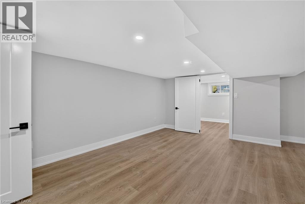 Recessed lighting, light wood-finish flooring, white trim, flat panel doors with dark hardware, and a window - 215 Paling Avenue, Hamilton, ON