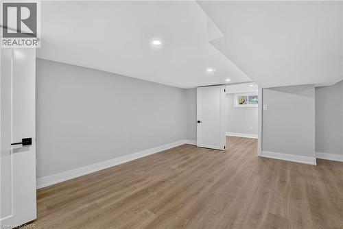 Recessed lighting, light wood-finish flooring, white trim, flat panel doors with dark hardware, and a window - 215 Paling Avenue, Hamilton, ON 