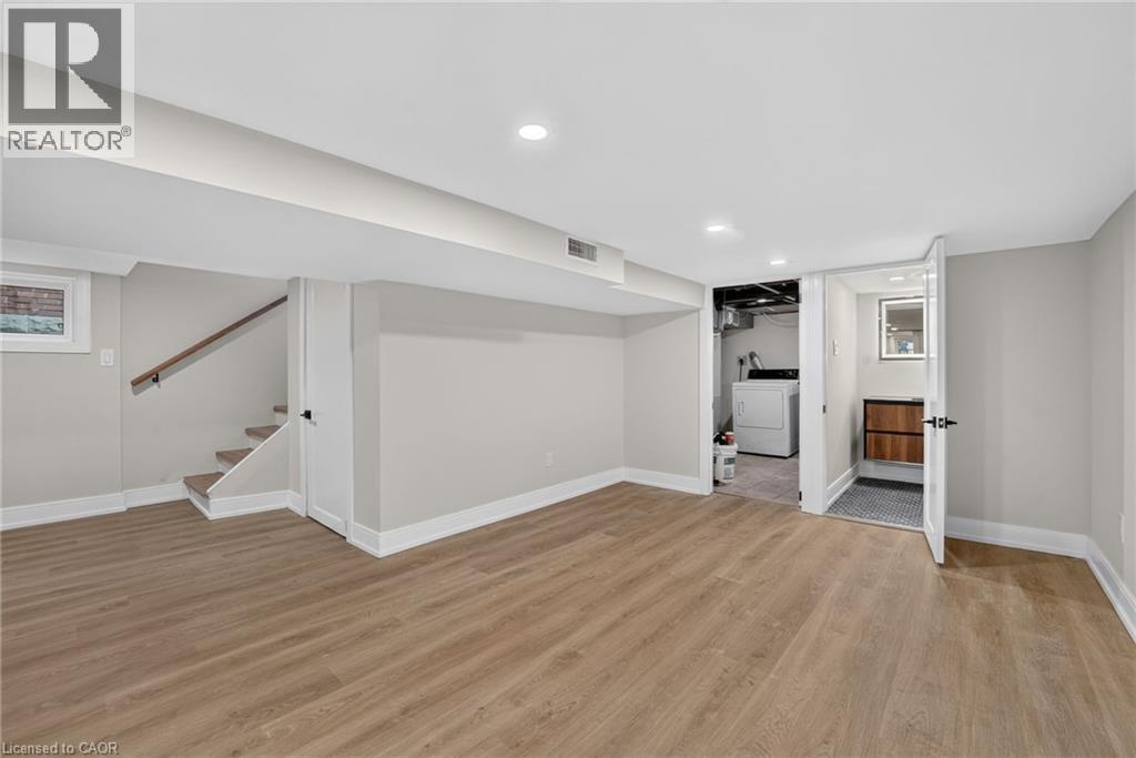 Spacious finished basement featuring wood-finish flooring, recessed lighting, and a dedicated laundry area - 215 Paling Avenue, Hamilton, ON