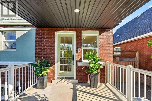 Brick exterior with light green entry door and white window trim - 215 Paling Avenue, Hamilton, ON 