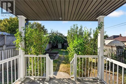 Covered porch entry featuring white railings and columns - 215 Paling Avenue, Hamilton, ON 
