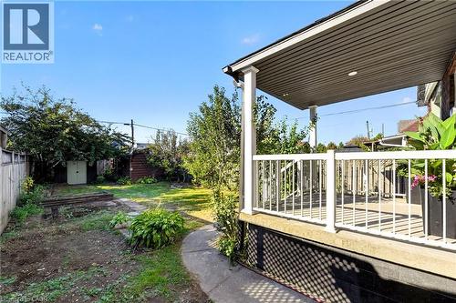 Expansive backyard with a covered patio, concrete pathway, and mature landscaping - 215 Paling Avenue, Hamilton, ON 