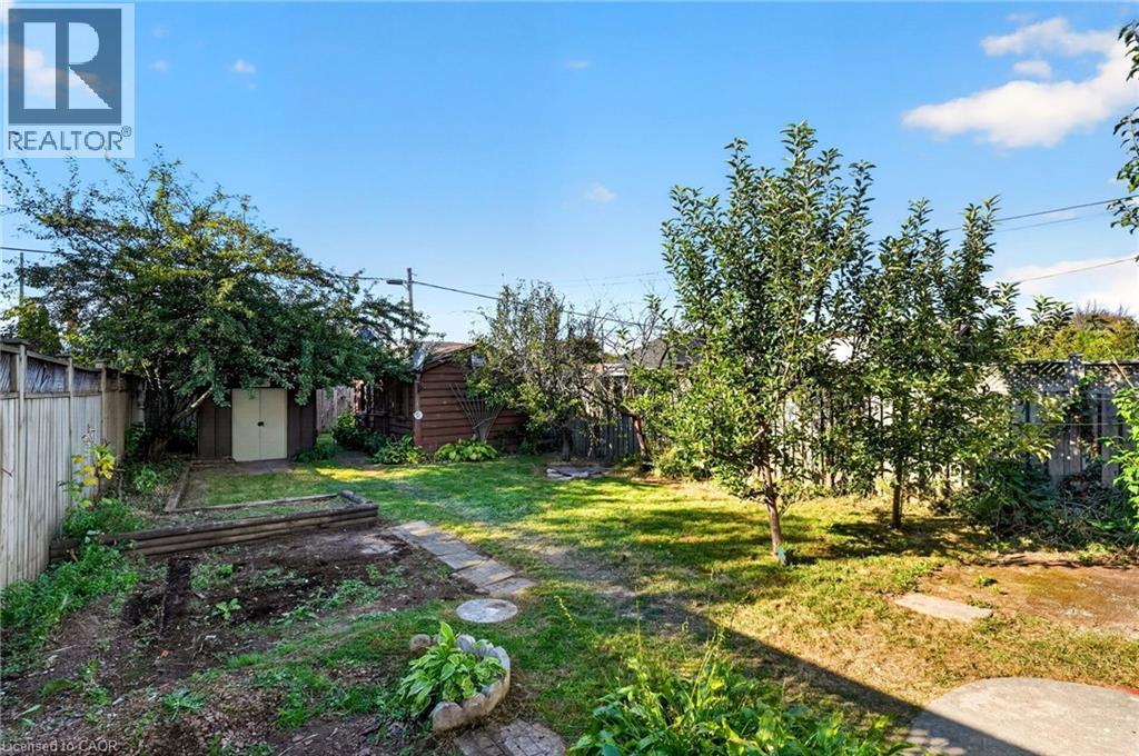 Expansive backyard featuring a fenced perimeter, established trees, a storage shed, and a path of stepping stones - 215 Paling Avenue, Hamilton, ON