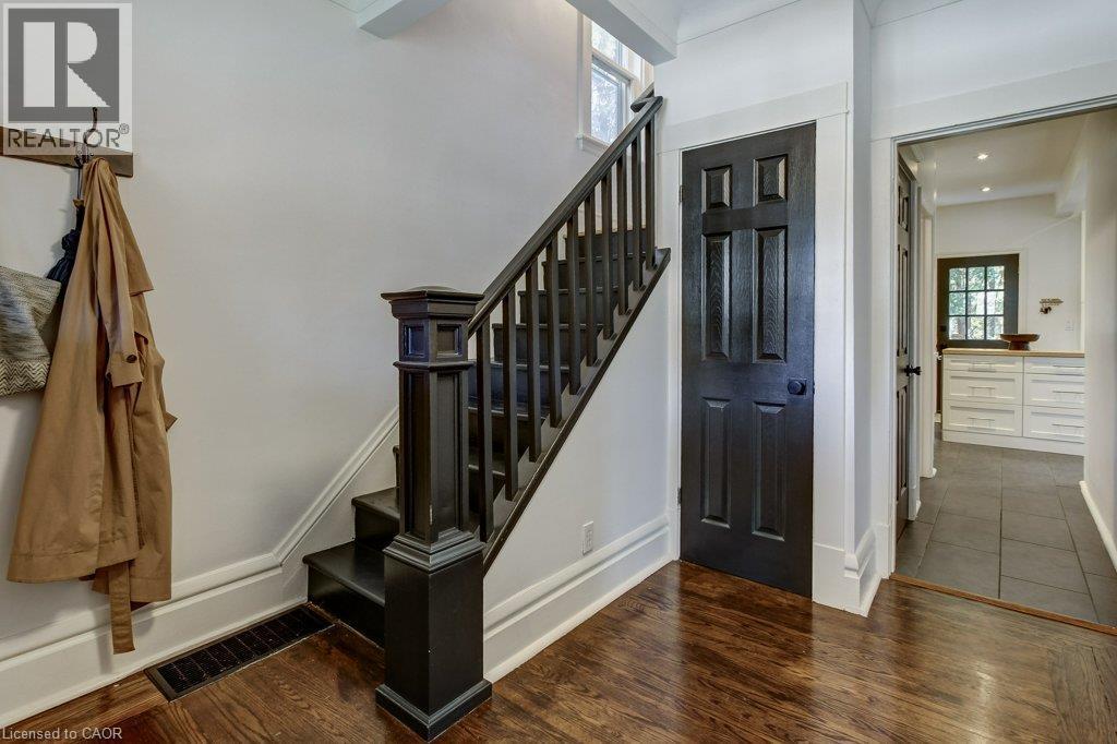 Hardwood flooring throughout, dark-finish staircase, paneled interior door, white baseboard trim, and recessed lighting - 43 Rosslyn Avenue S, Hamilton, ON