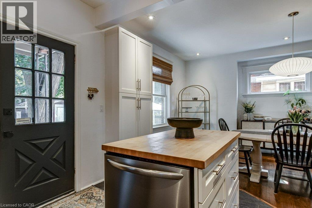 Kitchen featuring a butcher block island, stainless steel appliance, white cabinetry, dark wood-finish flooring, and recessed lighting - 43 Rosslyn Avenue S, Hamilton, ON