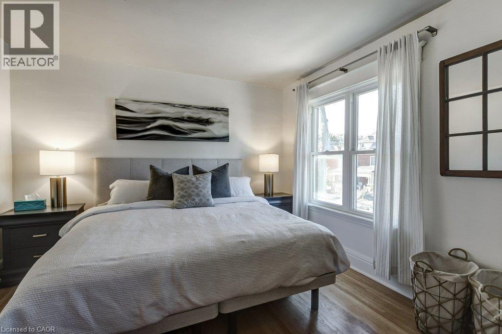 Hardwood flooring, light-toned walls, and a large window with white trim - 43 Rosslyn Avenue S, Hamilton, ON