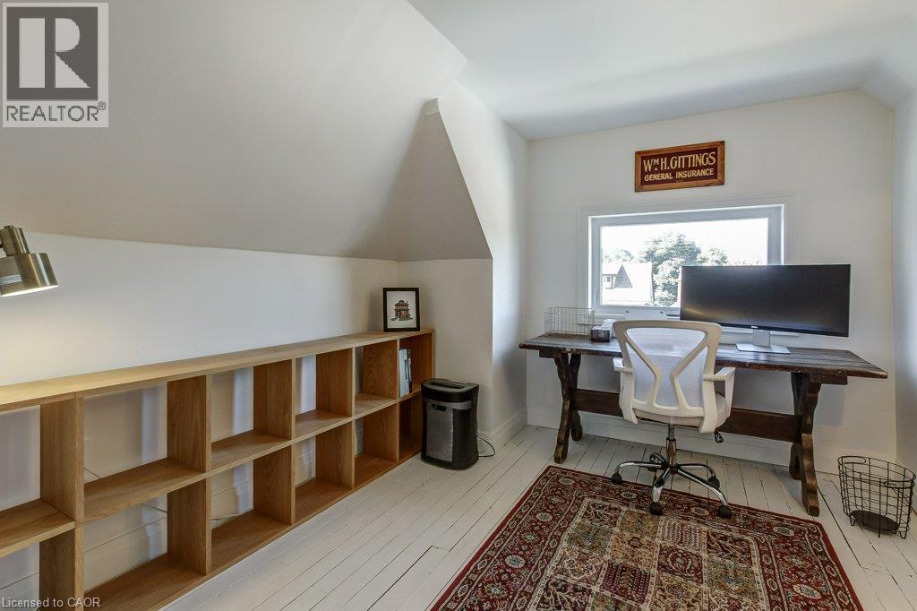Attic space featuring sloped ceilings, a wood-finish shelving unit, a window, and wood-finish flooring - 43 Rosslyn Avenue S, Hamilton, ON