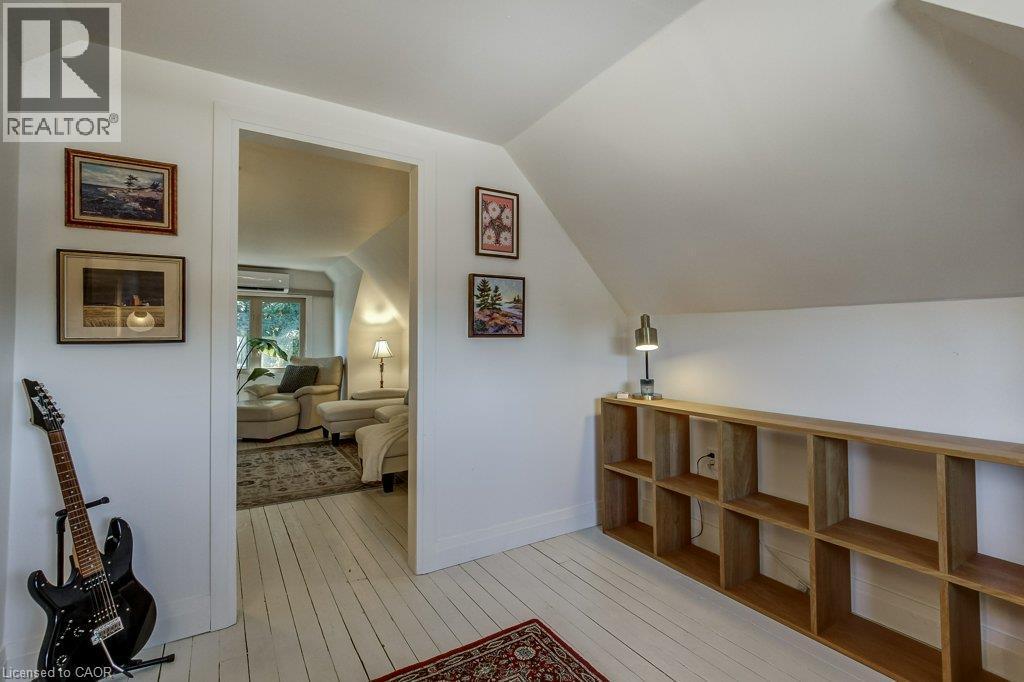 Attic space with painted wood-finish flooring, a shelving unit, and a doorway opening to an additional room - 43 Rosslyn Avenue S, Hamilton, ON