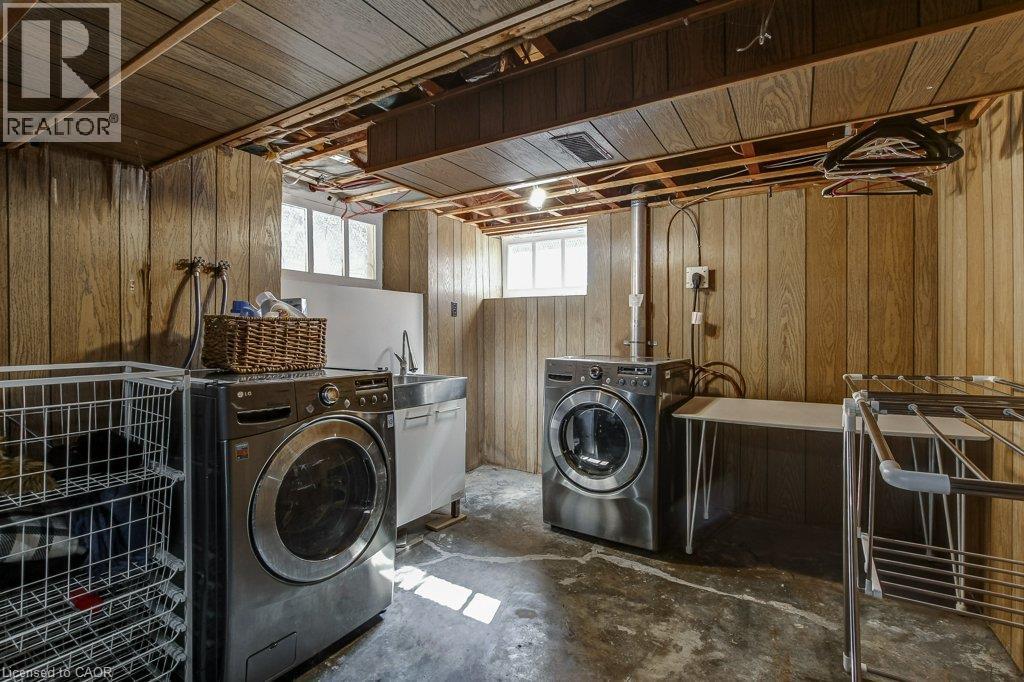 Laundry area with wood-finish wall paneling, exposed ceiling joists, and a utility sink - 43 Rosslyn Avenue S, Hamilton, ON