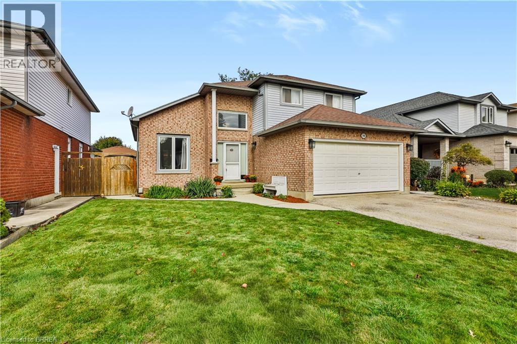 Brick and siding exterior with an attached garage, paved driveway, and established front landscaping - 19 Hyslop Drive, Caledonia, ON