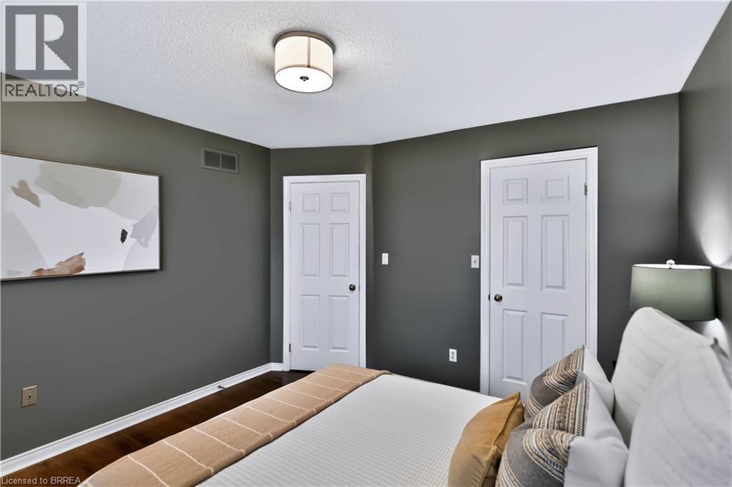 Wood-finish flooring with white trim, two white paneled doors, and a ceiling-mounted light fixture - 19 Hyslop Drive, Caledonia, ON
