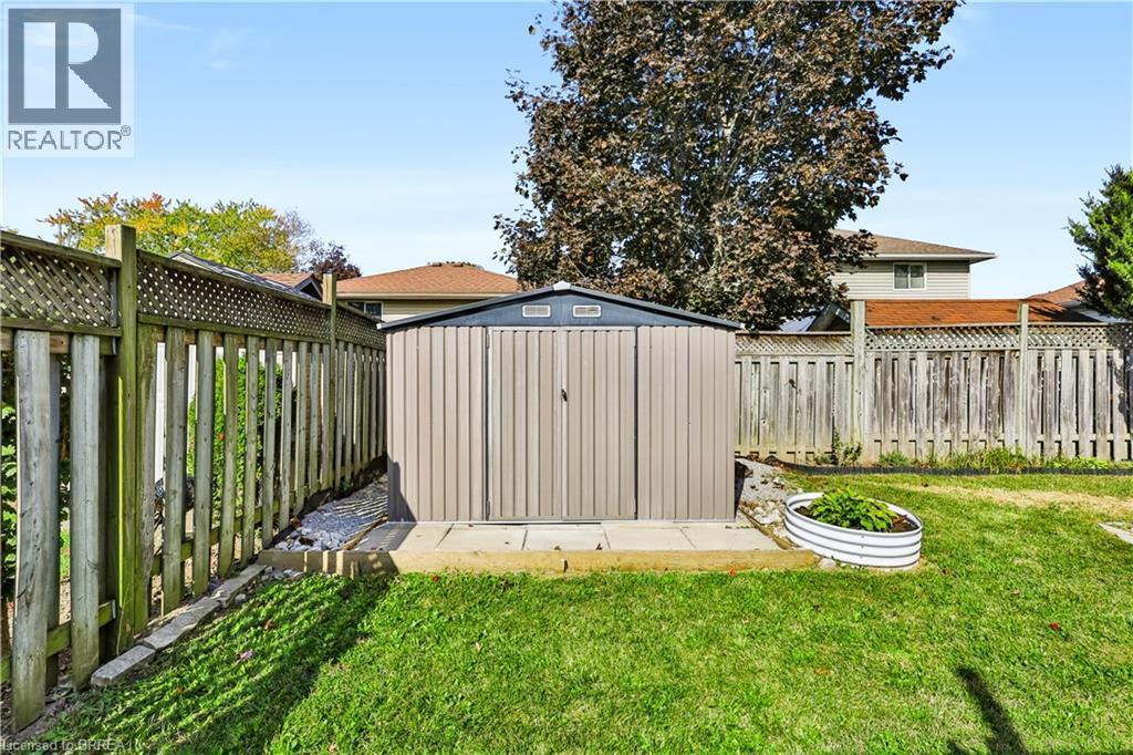 Expansive backyard featuring a manicured lawn, a metal storage shed on a concrete pad, and full perimeter fencing - 19 Hyslop Drive, Caledonia, ON