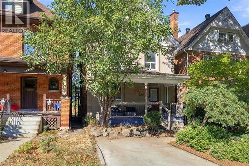 Stucco and brick exterior with a covered front porch, a gabled roofline, and front landscaping - 98 Sanford Avenue S, Hamilton, ON 