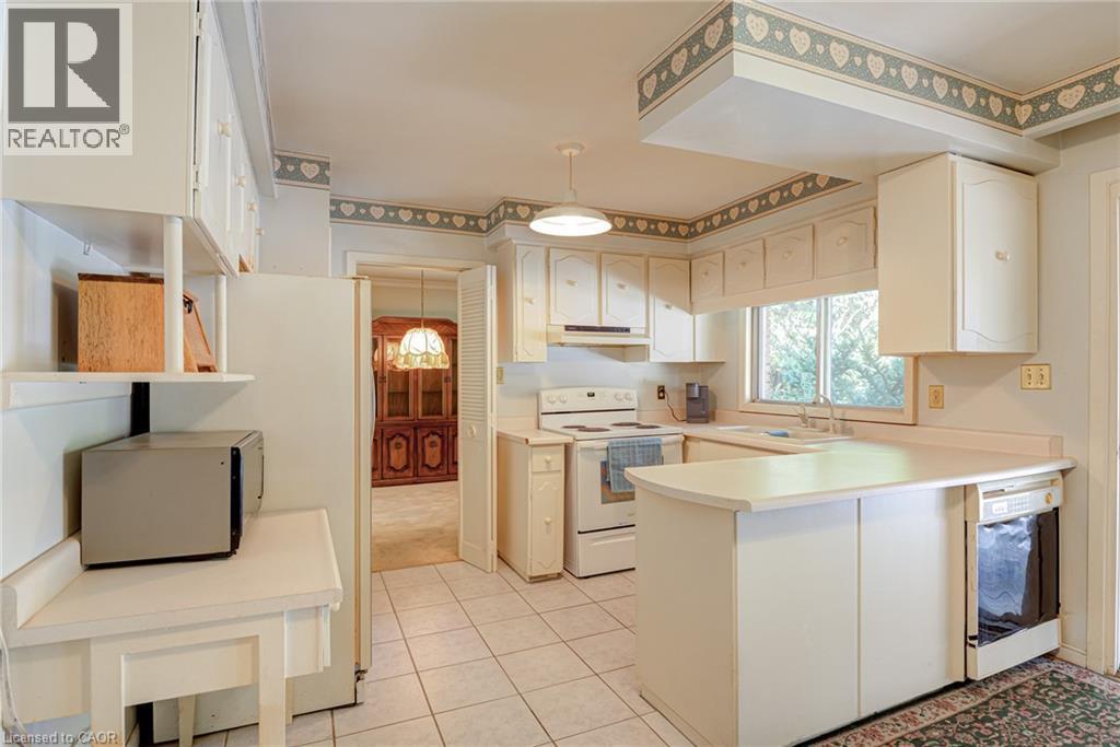 Kitchen featuring white cabinetry, tile flooring, a built-in dishwasher, a window over the sink, and a drop ceiling with decorative trim - 8 Bonnylyn Drive, Kitchener, ON