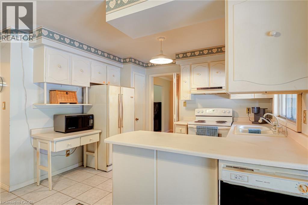 White cabinetry, tiled flooring, built-in desk, and a double basin sink - 8 Bonnylyn Drive, Kitchener, ON