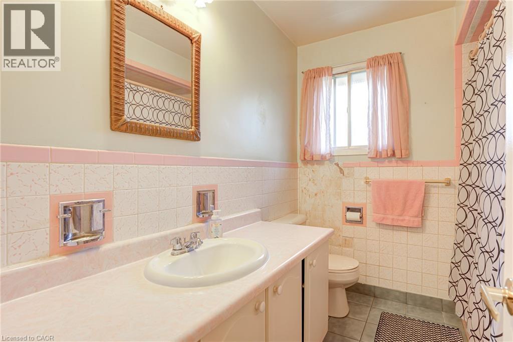 Single vanity with integrated sink, patterned wall tile, and a window for natural light - 8 Bonnylyn Drive, Kitchener, ON