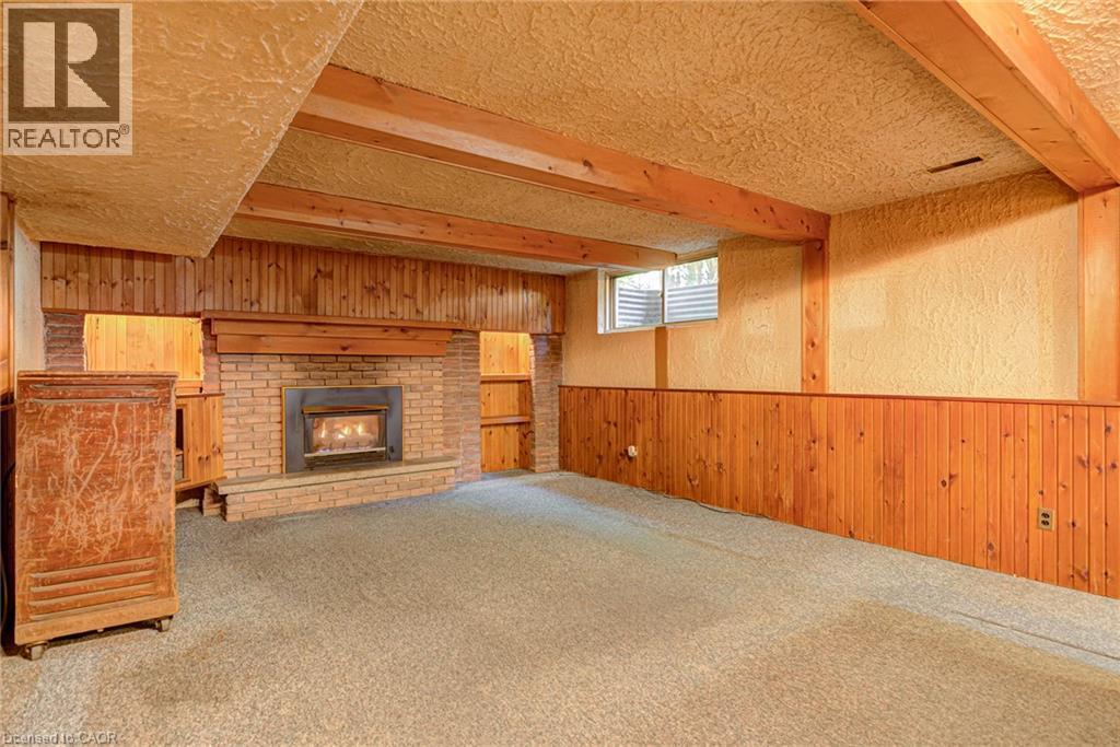 Brick fireplace with hearth, wood paneling, wood-beamed ceiling, and built-in shelving - 8 Bonnylyn Drive, Kitchener, ON